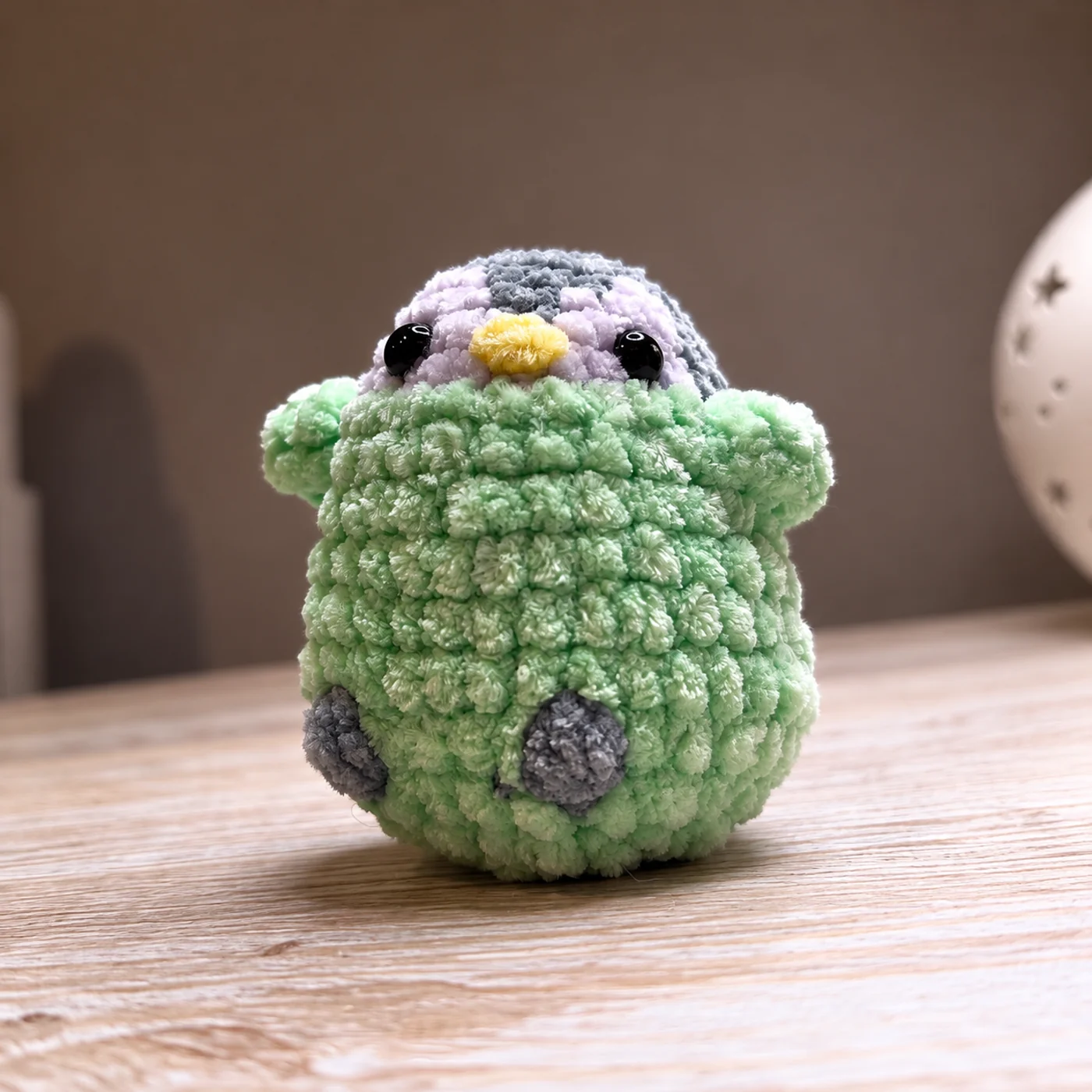 Photo of a small green penguin plush with a yellow beak and pale lilac details