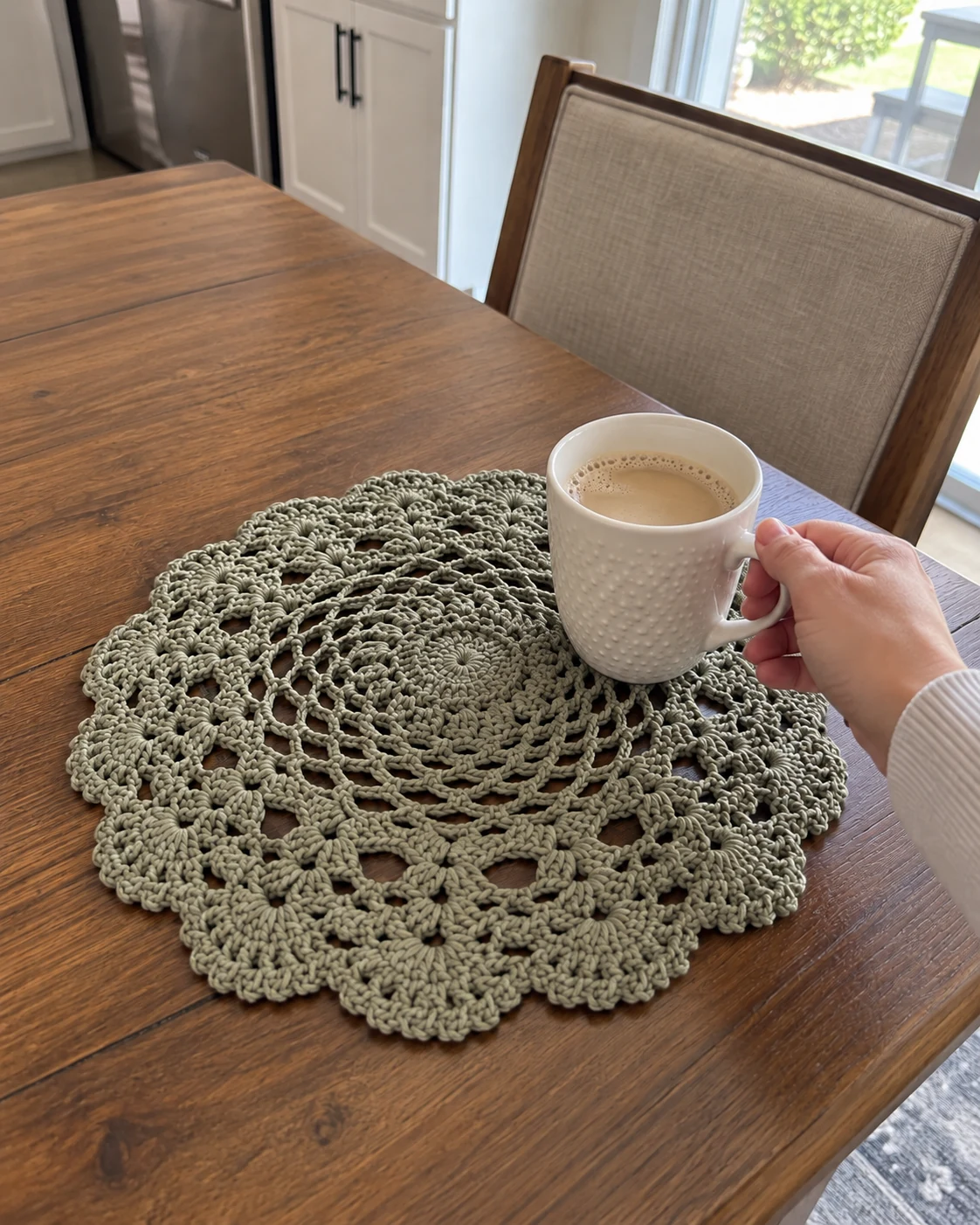 Photo of a round sage lace crochet placemat on a wooden table